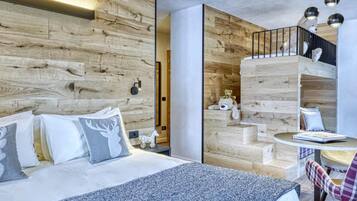 Une chambre moderne avec une tête de lit en bois, un lit avec une literie blanche, une petite table ronde avec une chaise et un escalier orné d’un ours en peluche.