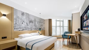 Ett modernt hotellrum med en stor säng, ett skrivbord, en stol och en väggmålning som föreställer en stadsbild.