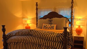 A four-poster bed with a striped bedspread, two bedside lamps, and a window with curtains. - Fabulous 3-bedroom house in Biddeford perfect for your beach getaway (Biddeford)