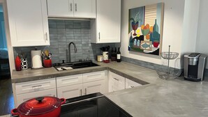 A modern kitchen with white cabinets, a black stovetop, and a red pot. - Fabulous 3-bedroom house in Biddeford perfect for your beach getaway (Biddeford)