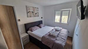 Ein Schlafzimmer mit einem Bett, Nachttischen, einem Fenster mit Jalousien und einem Bild an der Wand.