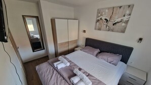 Quarto de hotel com cama, guarda-roupa, espelho e um quadro na parede.