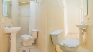 Un baño con dos inodoros, un lavamanos y una zona de ducha.