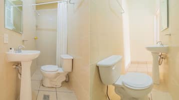 Un baño con dos inodoros, un lavamanos y una zona de ducha.