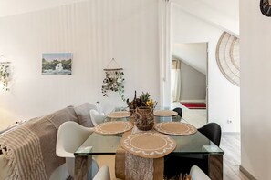 Un comedor moderno con una mesa de vidrio, sillas blancas y un adorno en la pared.