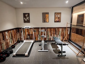 Een sportschool met trainingsapparatuur, een bank en een spiegel aan de muur.
