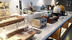 Balcão de pequeno-almoço com diversas opções de comida e eletrodomésticos, como torradeira e máquina de café.