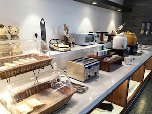 Een ontbijtbuffet met diverse etenswaren en apparaten, zoals een broodrooster en een koffieapparaat.