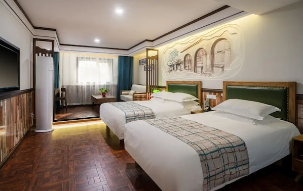 Een hotelkamer met twee bedden, een houten vloer, een groot raam met gordijnen en een wanddecoratie.