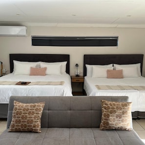Habitación de hotel con dos camas, un sofá y una mesita de noche.
