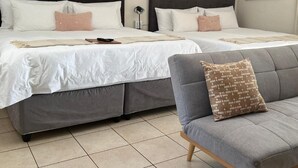 A hotel room with two beds, a grey sofa, and a painting on the wall. - Together Lifestyle Resort (Thulamela)