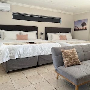 A hotel room with two beds, a grey sofa, and a painting on the wall. - Together Lifestyle Resort (Thulamela)