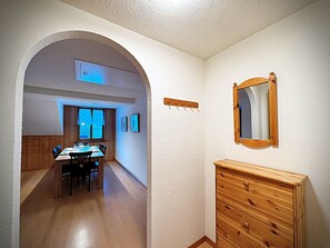 Ein Zimmer mit Esstisch für zwei Personen, einem hölzernen Schminktisch und einem Spiegel an der Wand.
