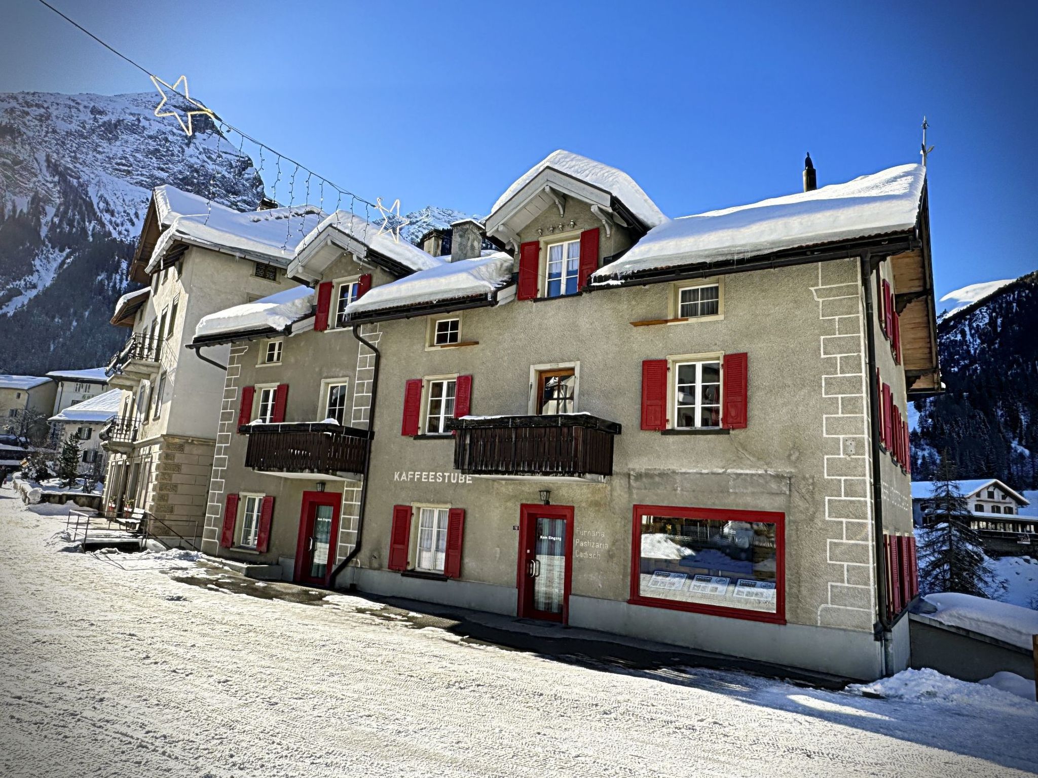 Un bâtiment doté de nombreuses fenêtres et de balcons, avec des toits enneigés et un paysage montagneux en arrière-plan.