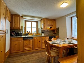 Eine Holz-Küche mit Essbereich, ausgestattet mit Schränken, einer Spüle und einem Fenster.