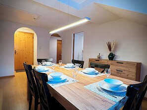 Ein Esszimmer mit einem langen Holztisch, gedeckt für vier Personen, Stühlen und einem Holzschrank.