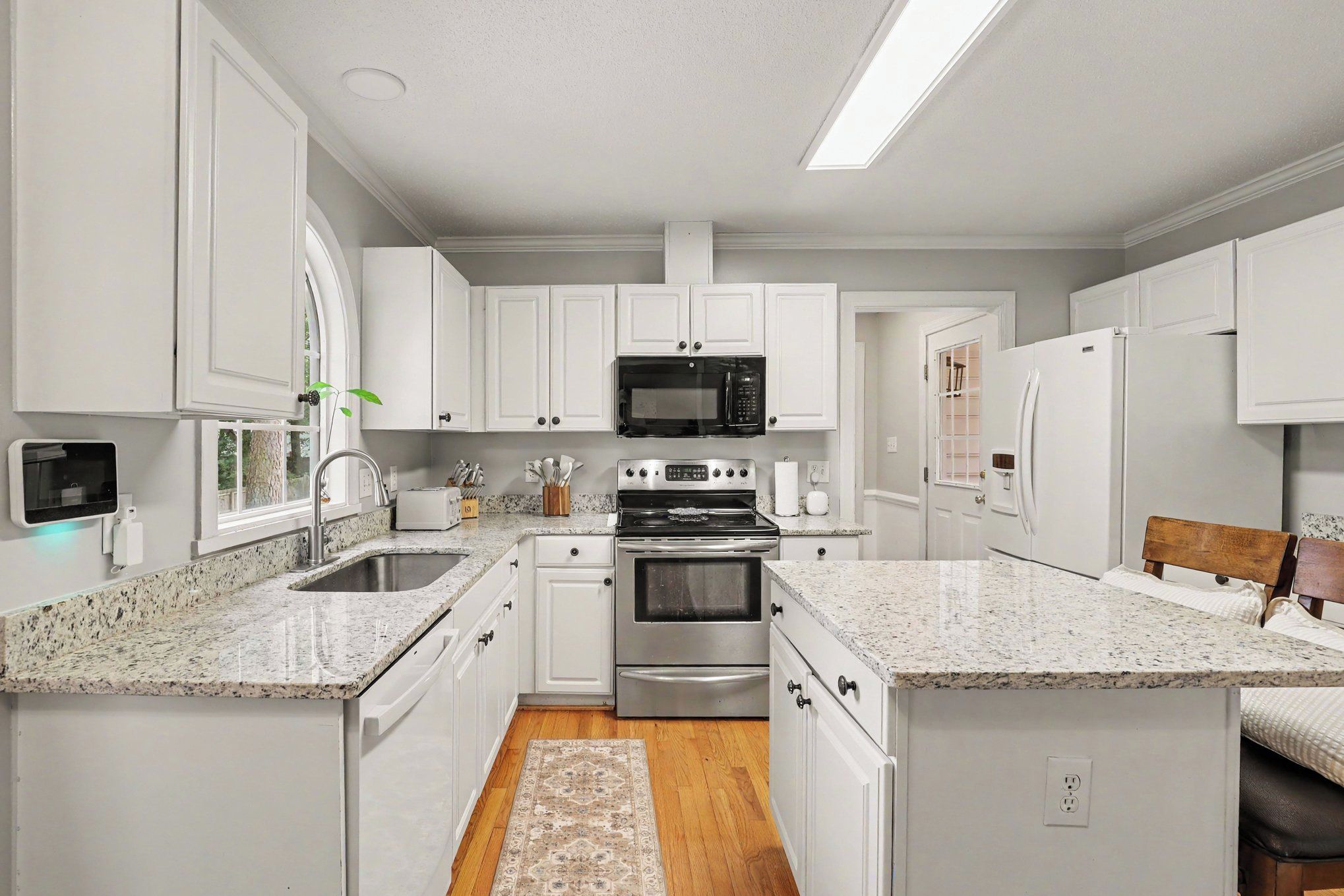 A modern kitchen with white cabinetry, stainless steel appliances, and a granite countertop.