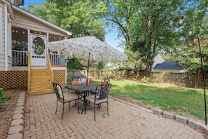Een terras met een tafel, stoelen, een parasol en een houten omheining.