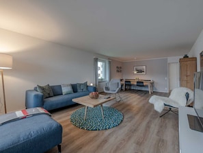 Ein modernes Wohnzimmer mit einer Couch, einem Couchtisch und einem runden Teppich.