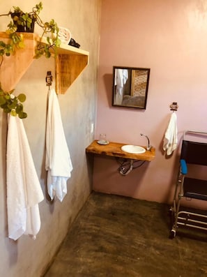 Un baño con tocador de madera, un lavabo, un espejo y toallas colgadas en la pared.