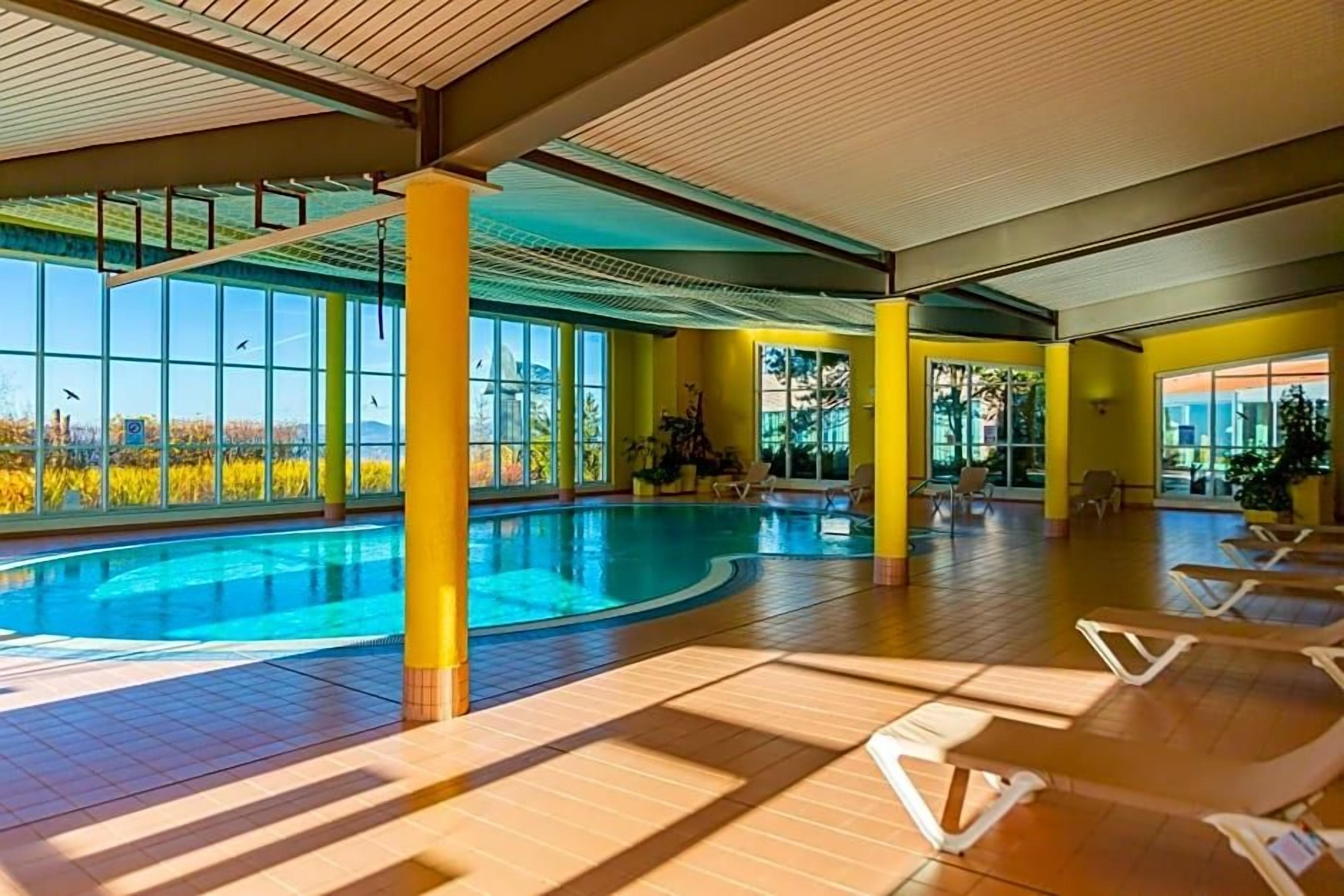 Ein Hallenbad mit sonnendurchfluteten Bereichen und Liegestühlen.