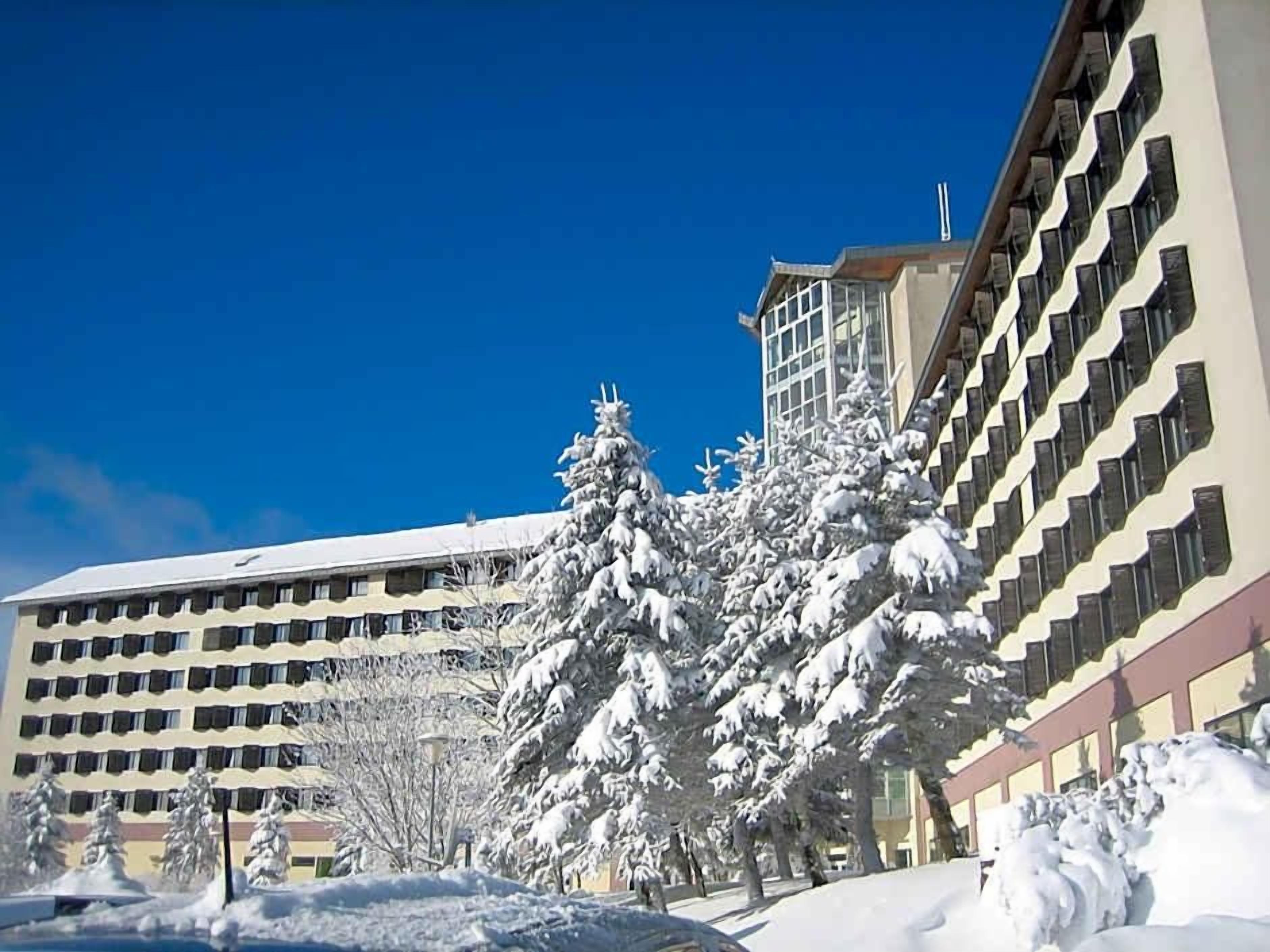 Ein mehrstöckiges Hotelgebäude mit einem schneebedeckten Baum davor.