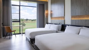 Een hotelkamer met twee bedden, een bureau en uitzicht op een golfbaan.