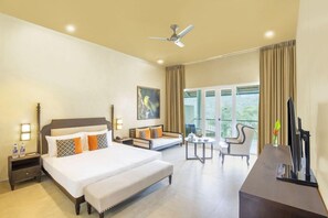 Habitación de hotel con una cama grande, un sofá, un escritorio y un balcón con cortinas.