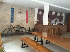 Un restaurante con un banco de madera, una bicicleta y una zona de bar con taburetes.