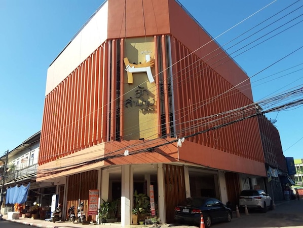 A hotel with a red facade, a visible entrance, and a sign indicating it's open.