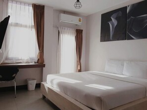 Una habitación de hotel con una cama, un escritorio, una silla y un equipo de aire acondicionado.