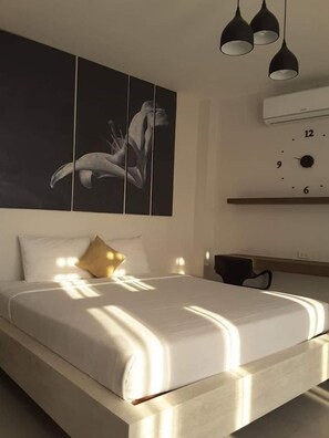 A modern bedroom with a large bed, a wall-mounted clock, and pendant lights.