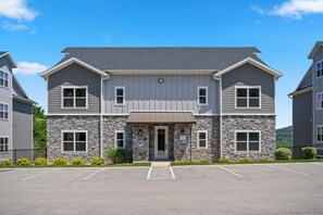 A two-story building with a stone facade, a central entrance, and a parking lot in front. - Walk-In 3BR | Fun Bunk Room + Arcade | Sleeps 9 (Branson)