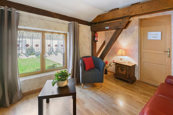 A room with a wooden staircase, a sofa, a small table with a plant, and a door labeled 'CUISINE'.