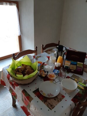 Ein Esstisch ist reichhaltig mit Speisen, einem Glas Orangensaft und einer Zigarettenpackung gedeckt.