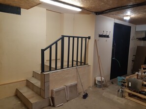 Eine Treppe mit schwarzer Geländer, ein Besen und Baumaterialien.