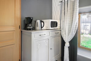A kitchenette with a coffee maker, a kettle, and a microwave on a white cabinet.