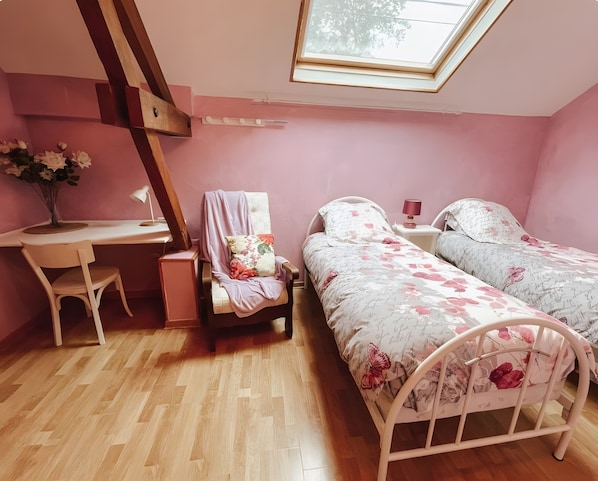 Ein Schlafzimmer mit Dachfenster, zwei Betten, einem Schreibtisch und einem Stuhl.