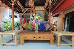 A traditional wooden bench with a vase of flowers, a cushioned seating area, and a decorative ceiling. - Ubud Asri by Zuzu (Ubud)