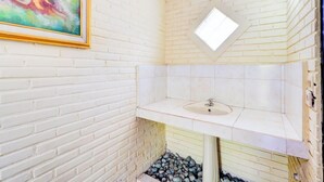 A bathroom with white brick walls, a white sink, and a skylight. - Ubud Asri by Zuzu (Ubud)
