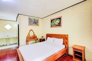 A bedroom with a wooden bed, a small bedside table, a mirror, and two framed pictures on the wall.