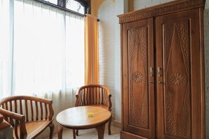 A room with a wooden cabinet, two chairs, and a small round table.