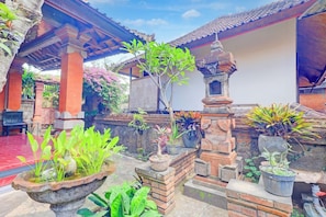 A courtyard with a traditional structure, potted plants, and a stone fountain.