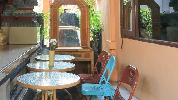 A small outdoor seating area with round tables and chairs, a mirror, and a view of greenery. - Ubud Asri by Zuzu (Ubud)