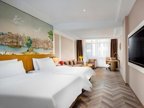 A hotel room with a large bed, a sofa, a desk with a laptop, and a TV. - Vienna Hotel (Changping)