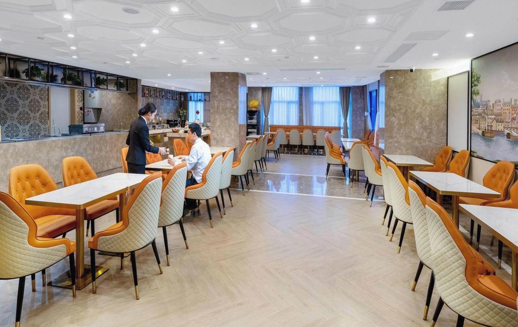 A spacious dining area with multiple tables and chairs, a bar area, and a view of the cityscape through large windows.