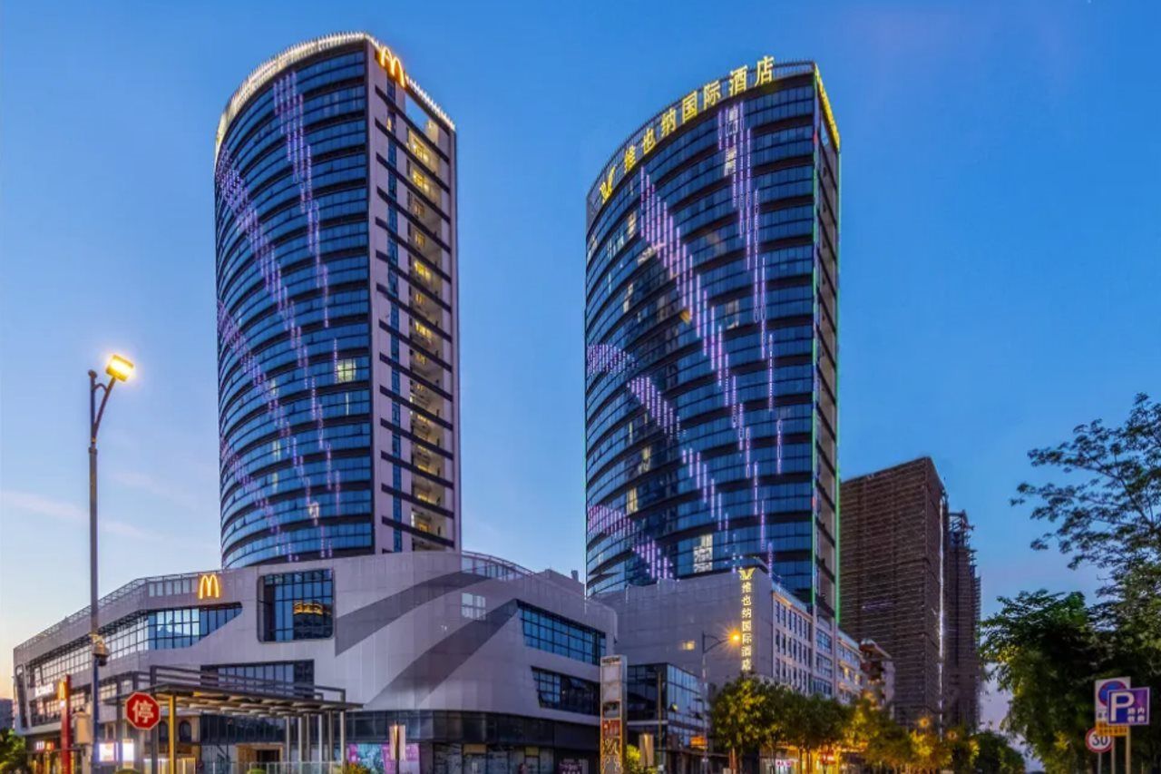 Two high-rise buildings with illuminated windows, a McDonald's restaurant, and a parking sign.