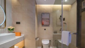 Een moderne badkamer met een douchecabine van glas, een wit toilet en een wastafel met spiegel.