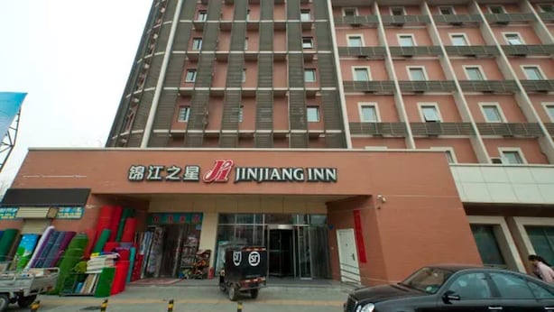 En bygning med flere etager, hvor 'JINJIANG INN' tydeligt er skiltet på stueetagen.