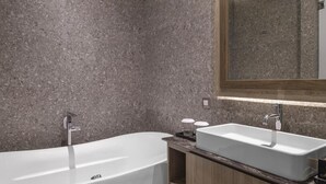 A modern bathroom with a freestanding bathtub, a vanity with a sink, and a large mirror. - The Margaux Hotel Yogyakarta (Yogyakarta)